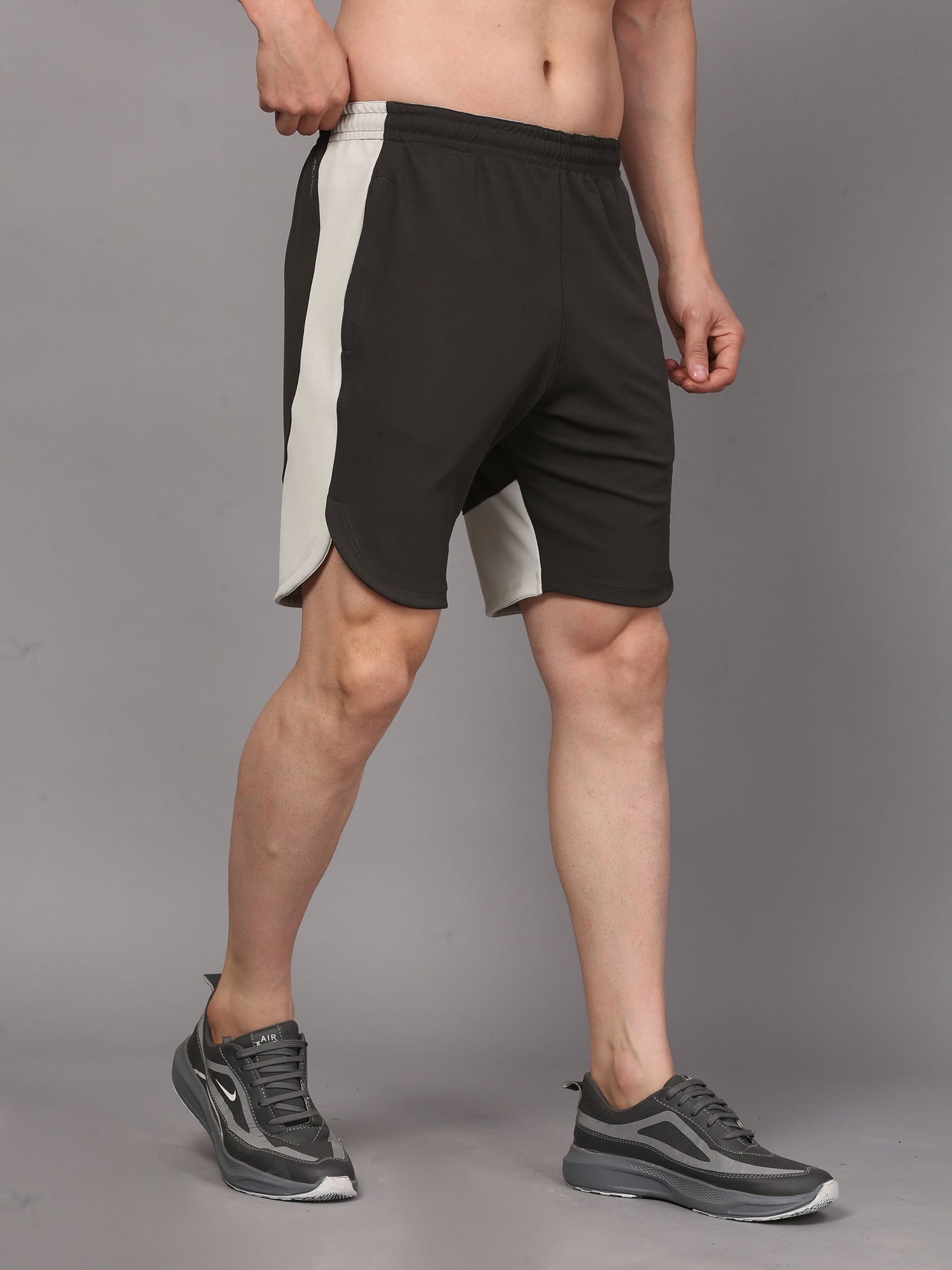 Person wearing black shorts with white stripes and gray sneakers