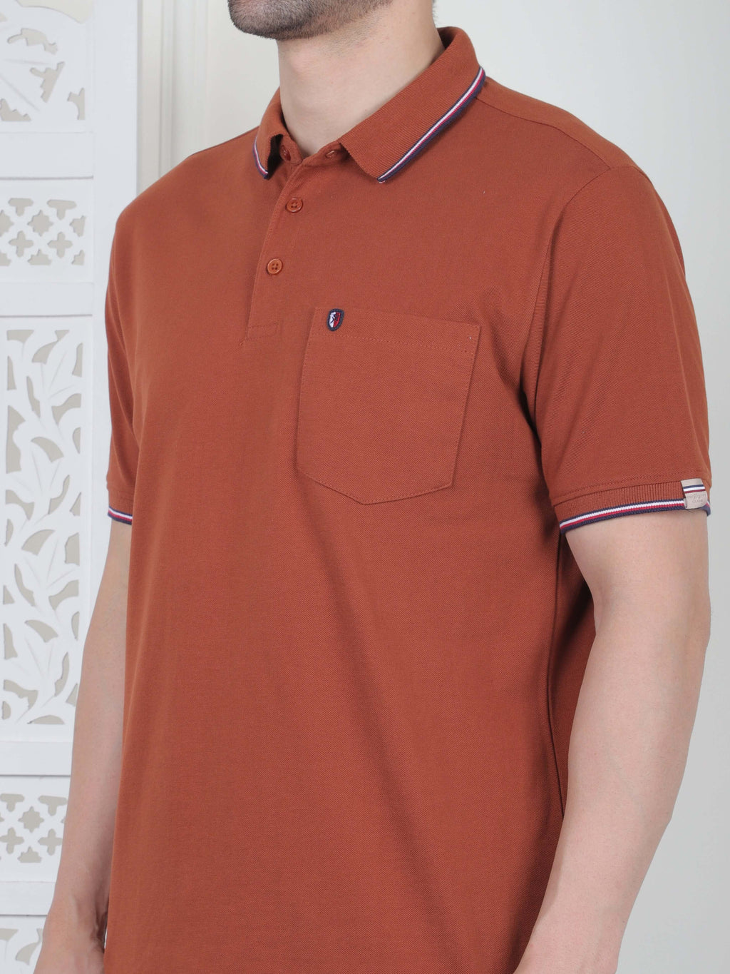 A rust brown polo shirt with pocket and piping details