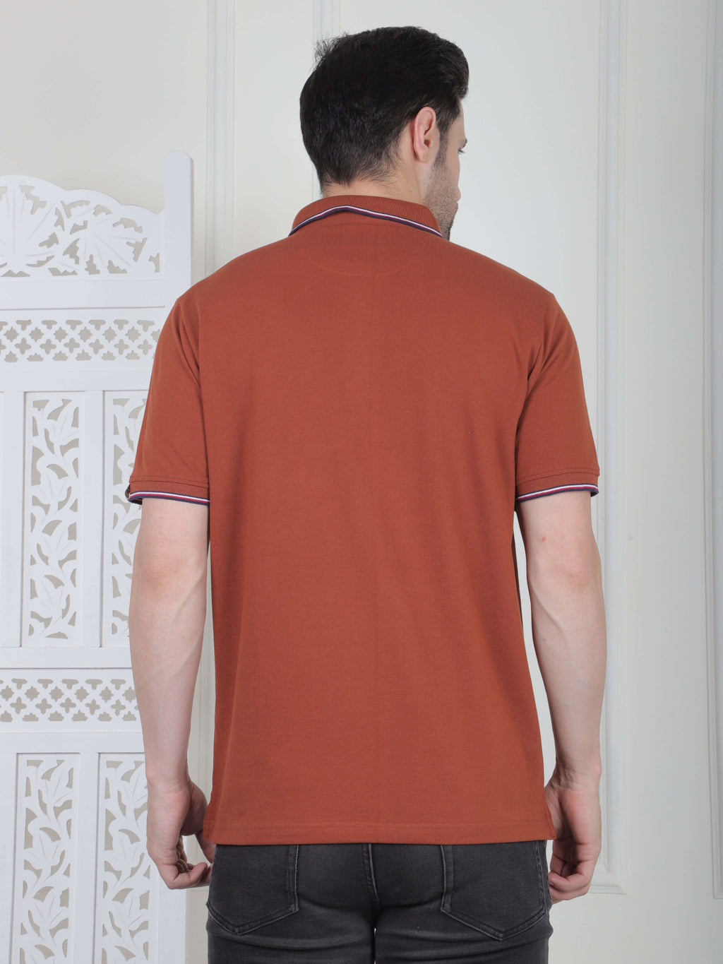 A rust brown polo shirt with pocket and piping details