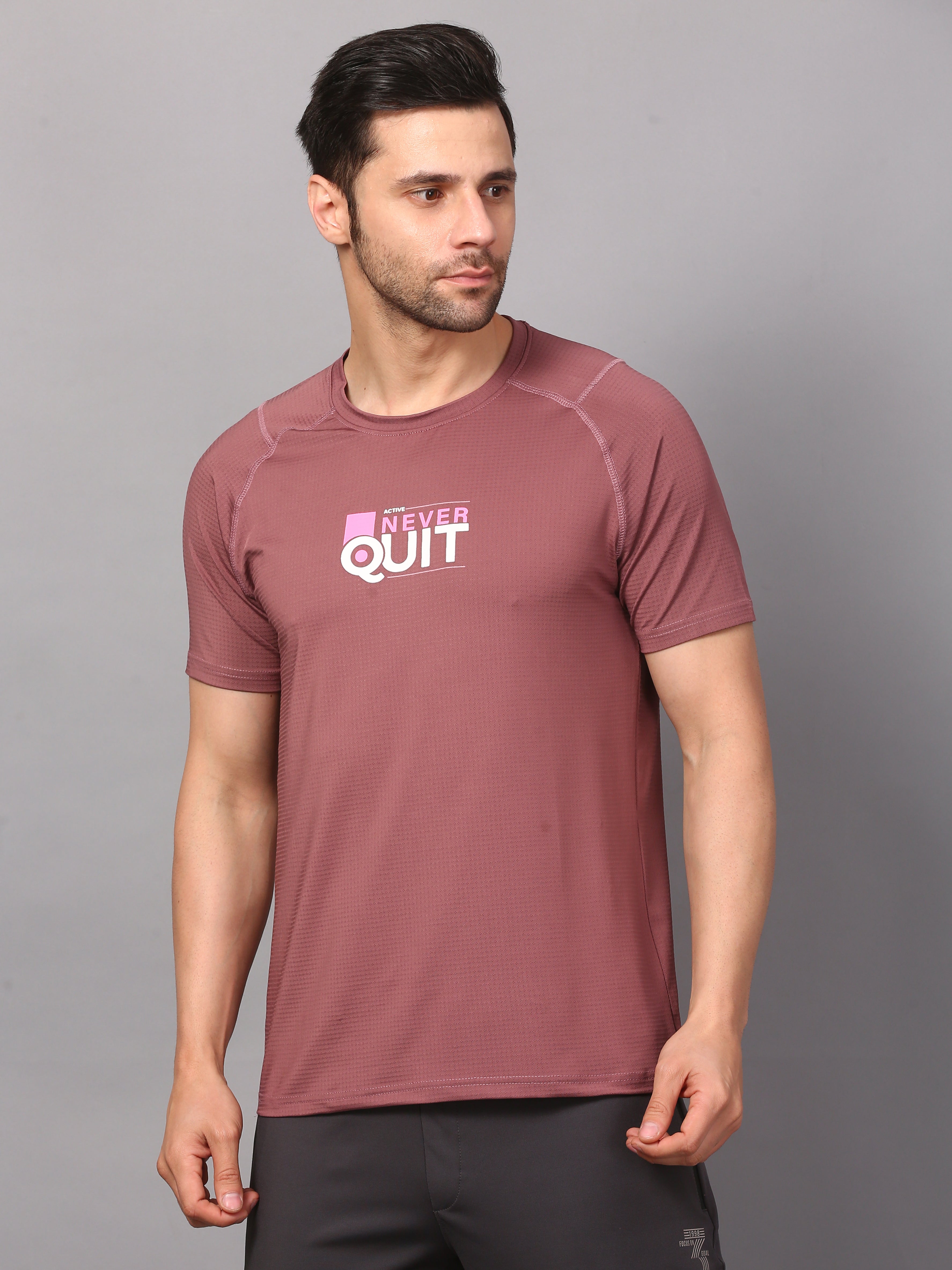 A man wearing a round neck mauve T-shirt with a logo on the chest.