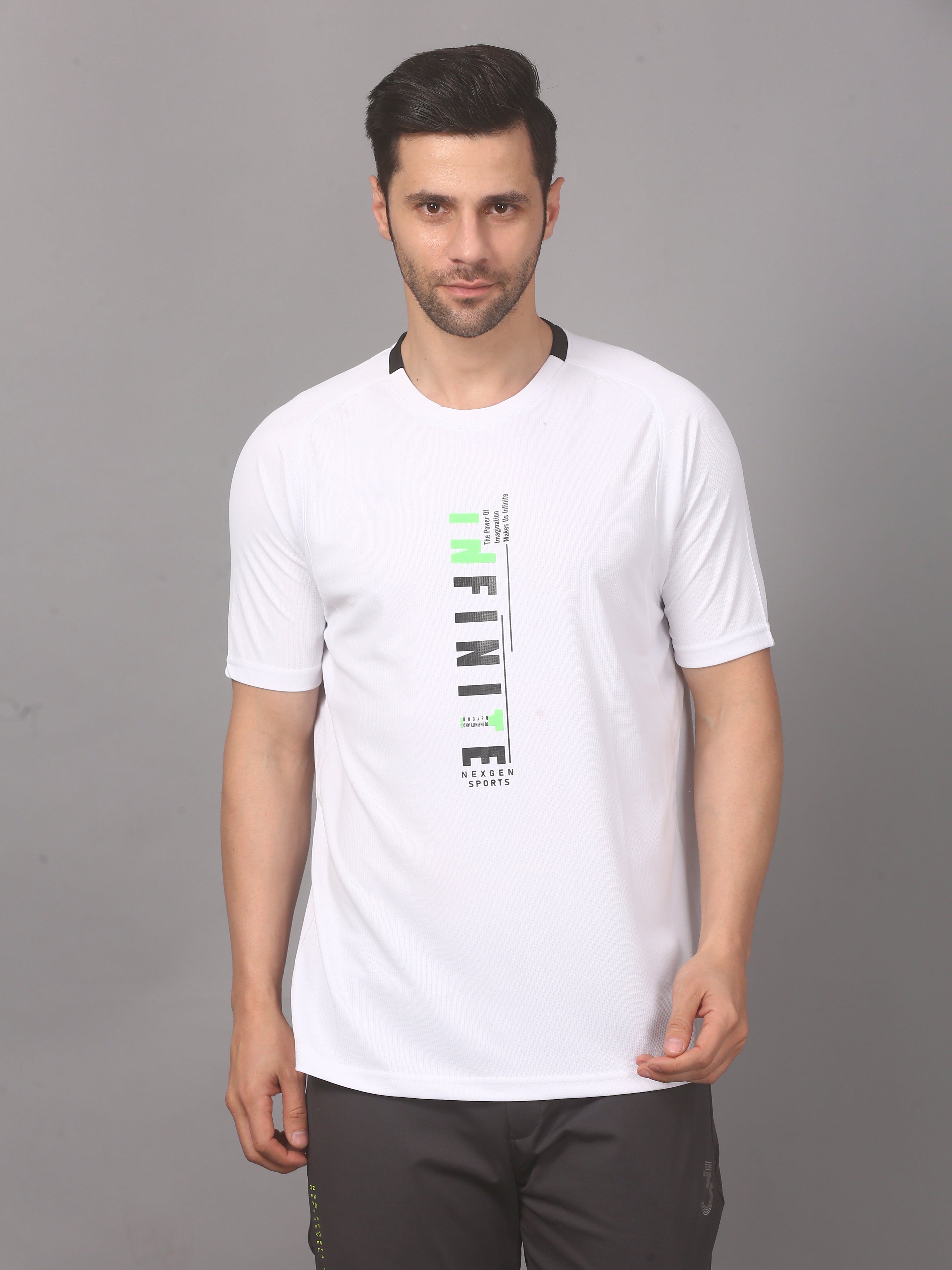 A man wearing a white round neck T-shirt with text on it, standing against a grey background.